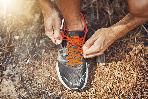 Shot of a young person tying their shoelaces before going for a run outdoors