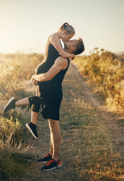 Shot of a young man kissing his girlfriend while he is lifting her outdoors