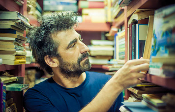 istock Curious man choosing book between the shelves in the library 691908534