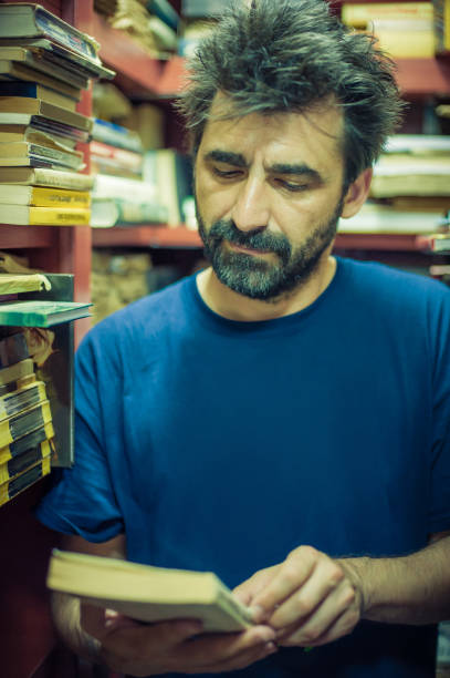 istock Curious man choosing book between the shelves in the library 691909112