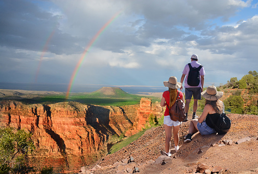 Family  hiking on vacation,relaxing on top of the mountain, looking at beautiful rainbow at sunset , mountains landscape. Grand Canyon National Park, Arizona, USA.