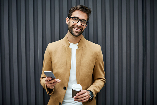 Happy businessman with smart phone and cup in city photo