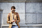 Smiling businessman using phone against building