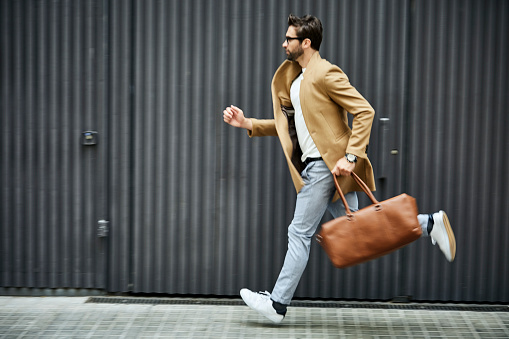 Businessman with bag running on sidewalk in city photo