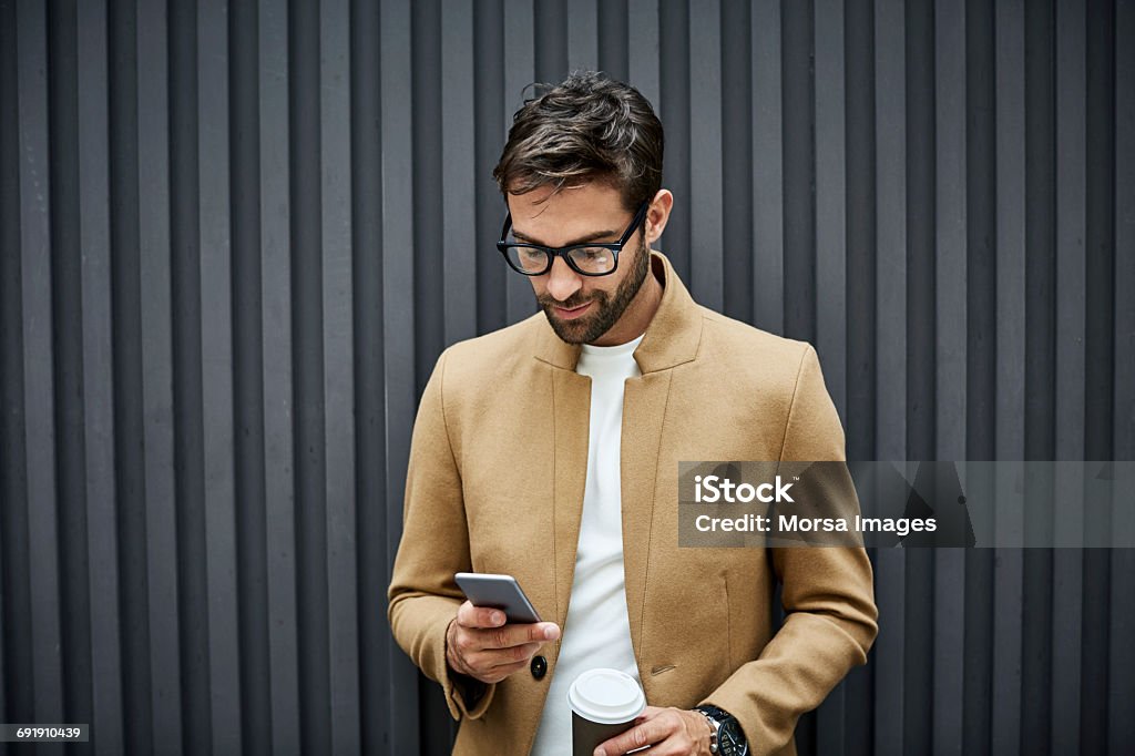 Businessman using phone and holding cup in city - Foto stock royalty-free di Uomini