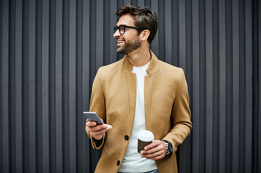 Smiling businessman with smart phone and cup photo