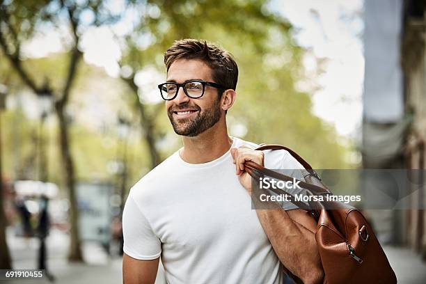 Smiling Businessman With Brown Bag Walking In City Stock Photo - Download Image Now - Men, Eyeglasses, Smiling