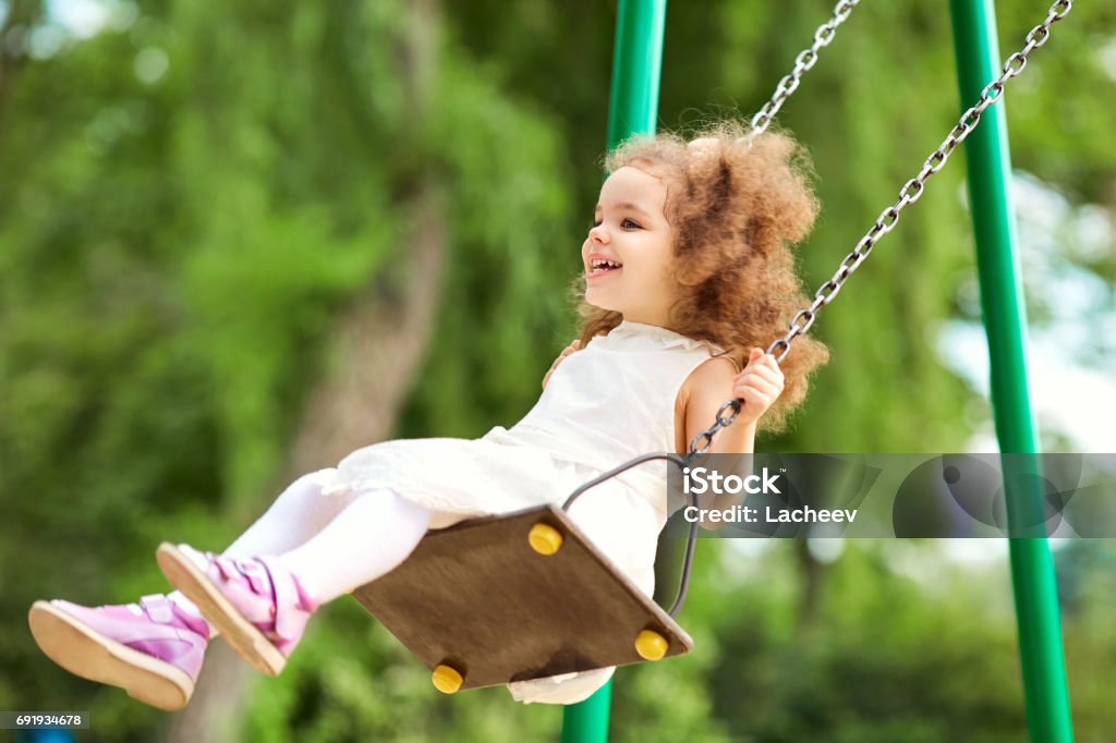 Enfant se balancer sur une balançoire au terrain de jeux dans le parc. - Photo de 2-3 ans libre de droits