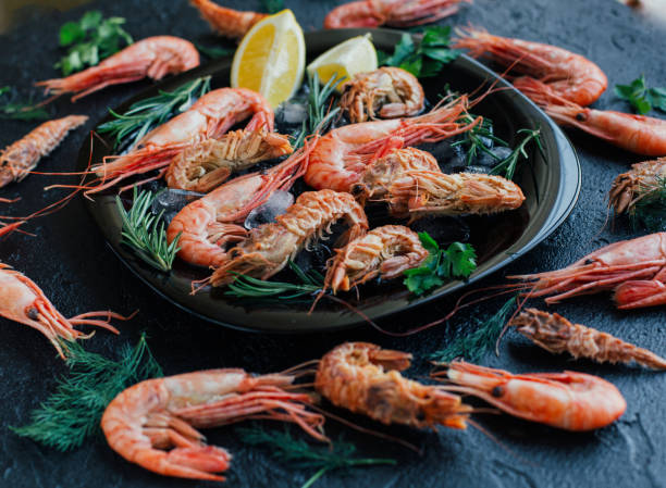 istock Tiger shrimps with lemon, rosemary on stone background. 691946864