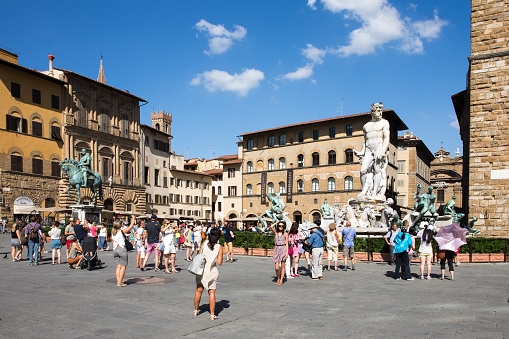FLORENCE, ITALY - July 28, 2015:  Piazza della Signoria, or Signoria Square, in Florence, Italy taken during the summer and showing tourists, the Fountain of Neptune, and other historic statues and buildings.  The square is a focal point of the city and a meeting place for Florentines and tourists alike.