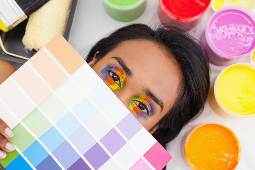 Portrait of a young woman with paint samples over white background