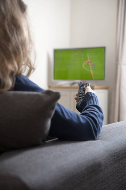istock Woman sitting on sofa with remote control in her hand, while watching television in the domestic living room at home 691969498