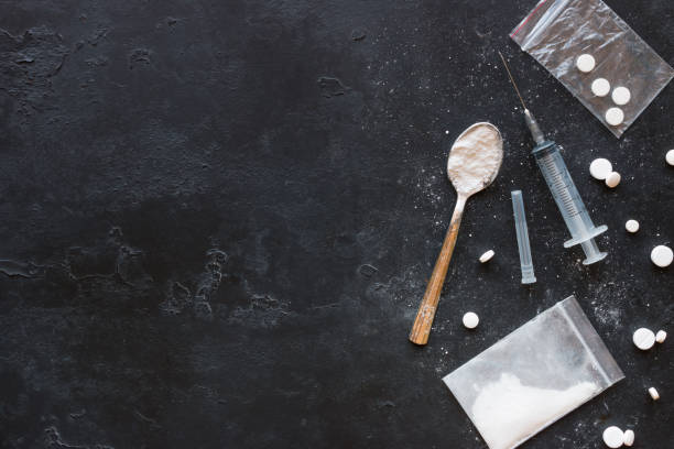 Drugs in the form of powder and tablets, a spoon and a syringe on a black background mockup Drugs in the form of powder and tablets, a spoon and a syringe on a black background mockup cocaine stock pictures, royalty-free photos & images
