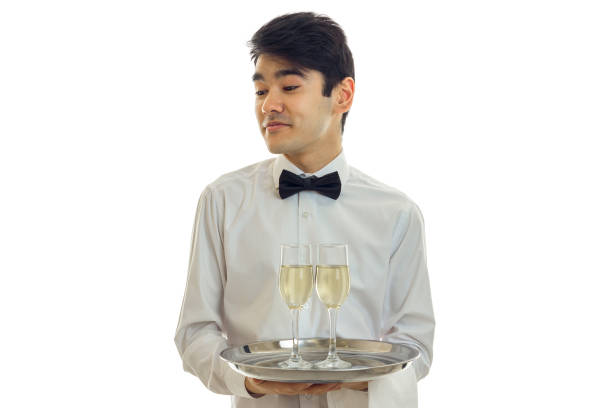handsome young waiter turned his head and holding a champagne glasses on a tray that