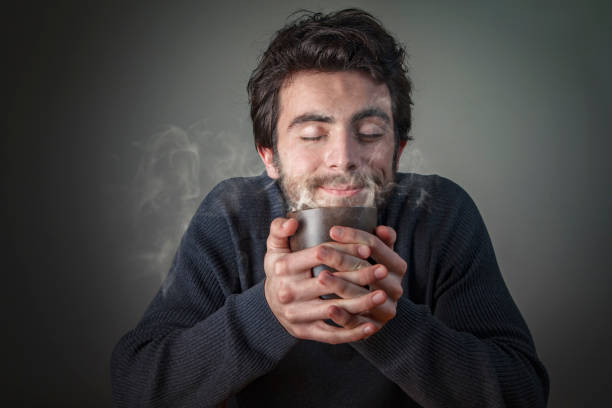 Young attractive caucasian man enjoying the smell of a freshly brewed coffee or tea