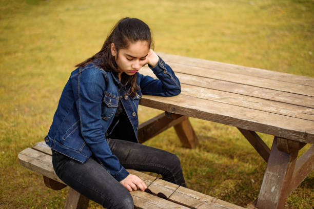 unhappy girl sitting at picnic table - one person child serene people failure imagens e fotografias de stock