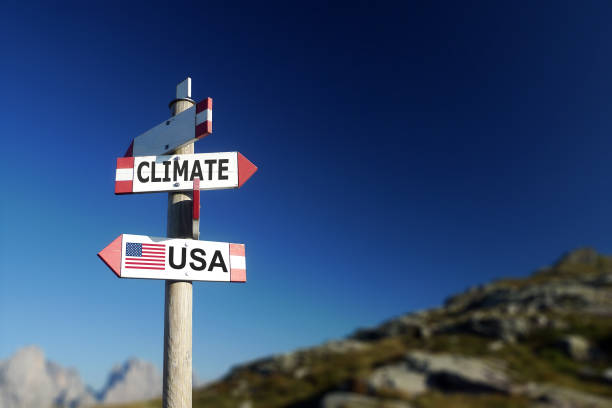 zmiany klimatu i amerykańska flaga w dwóch kierunkach na znaku drogowym. wycofanie umowy klimatycznej. - protokół z kioto zdjęcia i obrazy z banku zdjęć