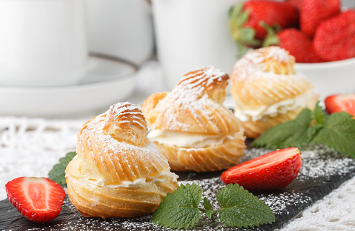 Homemade profiteroles with cream, strawberries and mint. Dessert for gourmets. Selective focus