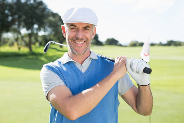 istock Golfer standing and swinging his club smiling at camera 692077384