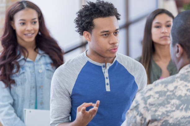 istock Inquisitive young man asks military recruiter questions at recruitment event 692087904