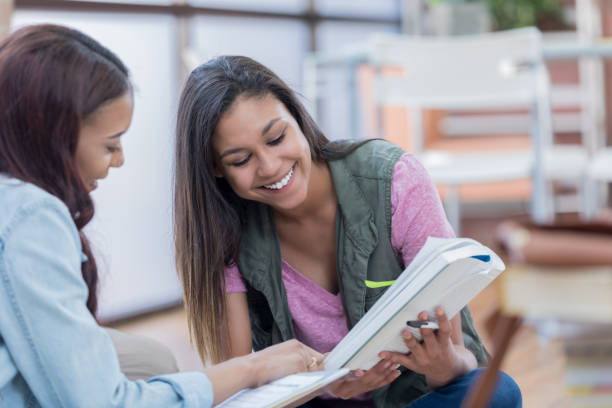 istock Female college student look at book together 692087928