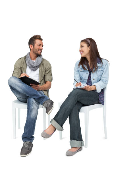 pareja joven cool escribir en libretas - talking chair two people sitting fotografías e imágenes de stock