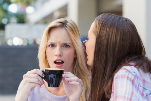 istock Brunette telling secret to her friend while drinking coffee 692103154