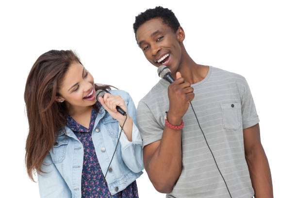 istock Young couple singing into microphones 692103230