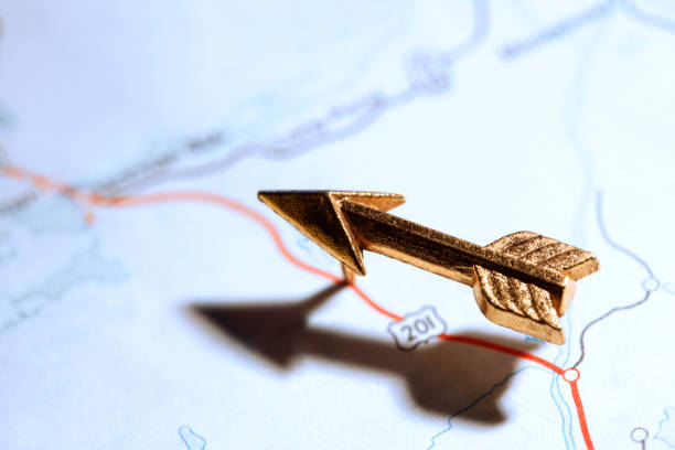 A gold arrow push pin points the way on a generic road map.  Image is captured using a very shallow depth of field.