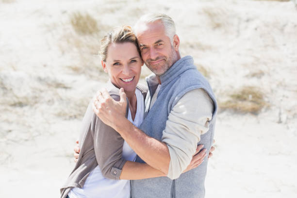 istock Happy couple hugging on the beach looking at camera 692109268