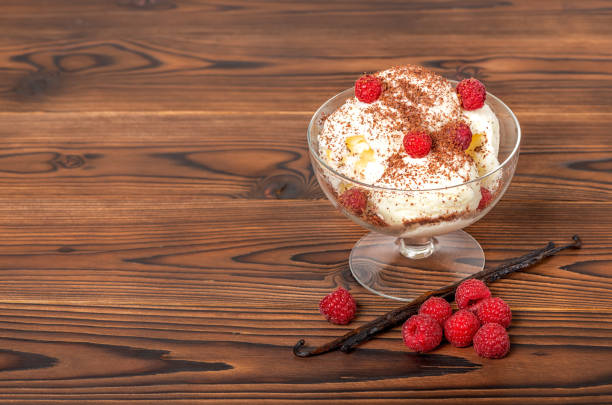 Raspberry dessert with whipped cream in bowls on a red towel with a blurred forest in the background