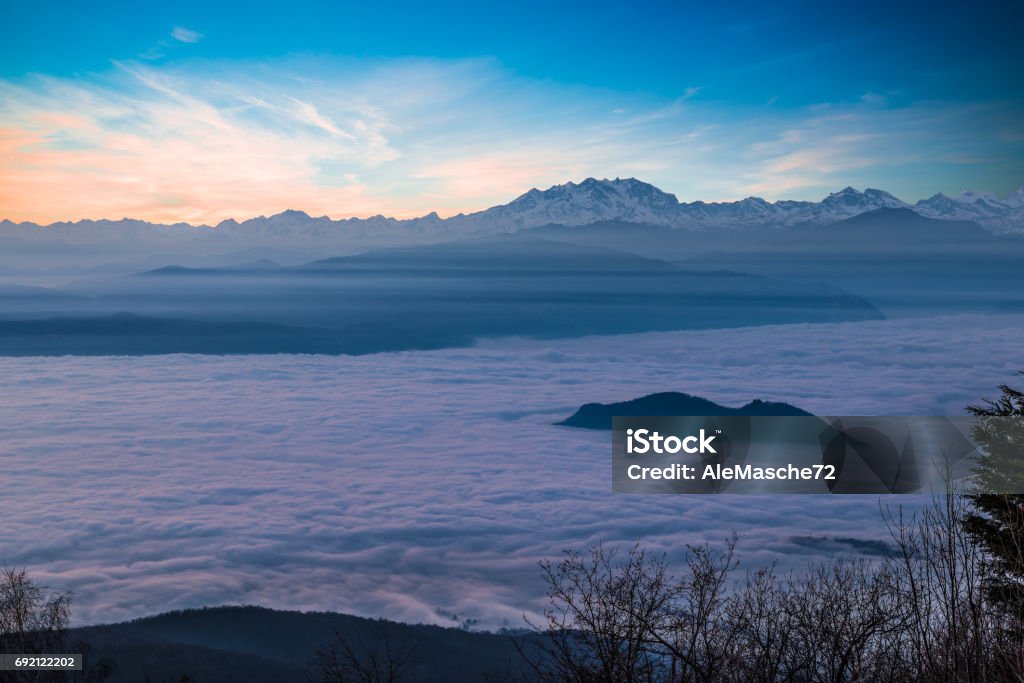 Alpine chain with Monte Rosa emerges from a sea of clouds at sunset. Aerial view from Campo dei Fiori of Varese, Italy. Winter high pressure and example of atmospheric stratification Monte Rosa at sunset. Spectacular sea of fog on the Padan Plain and Lake Maggiore area, from Campo dei Fiori of Varese, province of Varese, northern Italy Winter Stock Photo