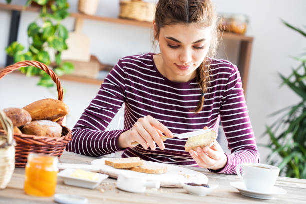 버터와 빵을 먹는 젊은 여자 - basket bread breakfast close up 뉴스 사진 이미지