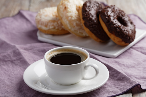 Cup of coffee and donuts with chocolate and white frosting