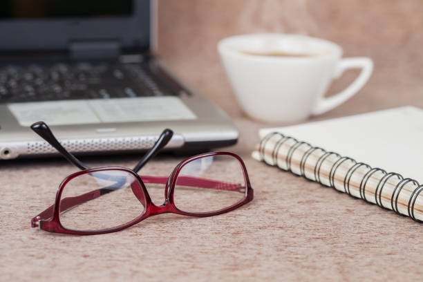 istock Selective focus office table : eyeglass , laptop, note book and cup on the wooden 692162026