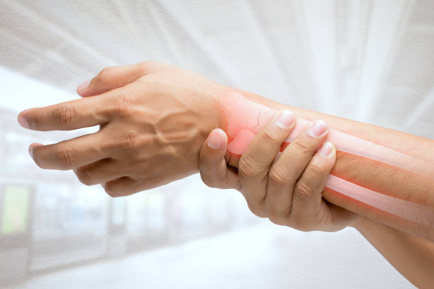 hombre masaje muñeca dolorosa sobre un fondo blanco. concepto de dolor - fracture fotografías e imágenes de stock