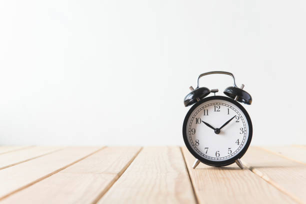 istock Black alarm clock on a wooden table in a wall 692171924