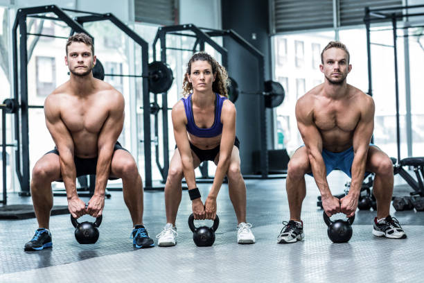 istock Three muscular athletes about to lift a kettle bell 692172300