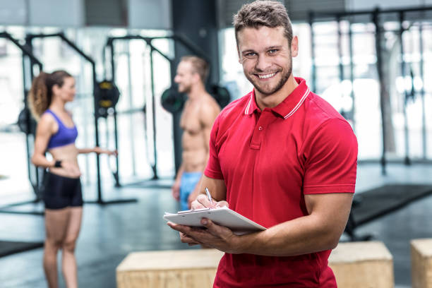 istock Smiling muscular trainer writing on clipboard 692173084