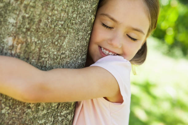 istock Smiling girl hugging tree with eyes closed at park 692176026