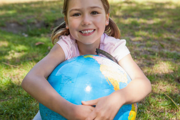 istock Cute young girl holding globe at park 692178348