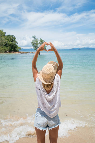 istock Woman making heart shape frame on tropical beach landscape 692179052