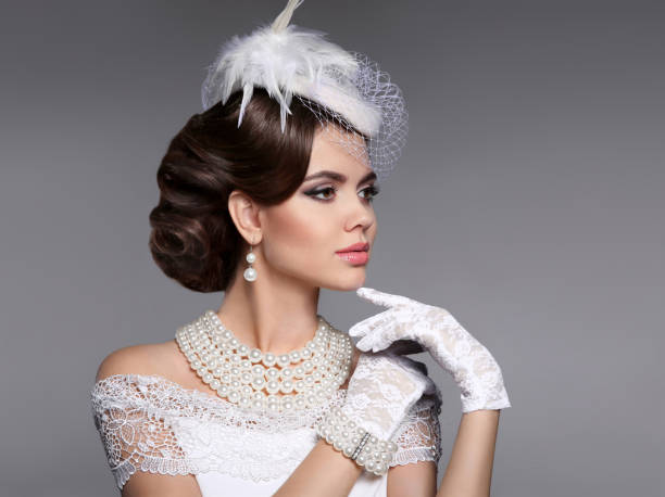 Retro woman portrait. Elegant lady with hairstyle, pearls jewelr Retro woman portrait. Elegant lady with hairstyle, pearls jewelry set wears in hat and lace gloves posing isolated on studio gray background. hairstyle bride jewelry women stock pictures, royalty-free photos & images