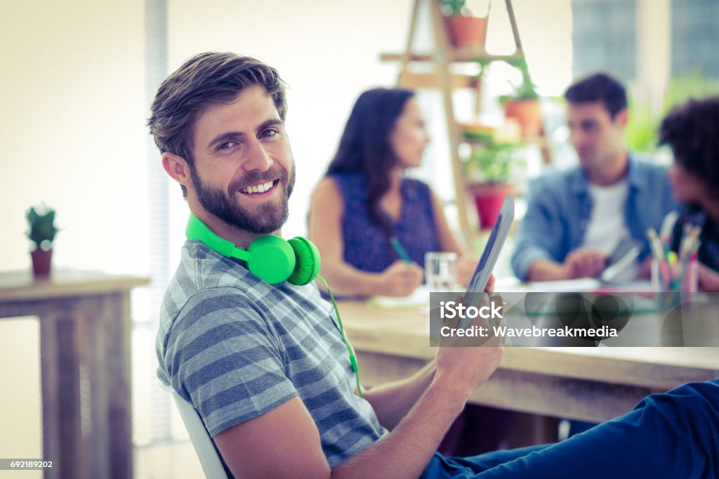 Smiling young man using digital tablet Smiling young man using digital tablet in the office 20-24 Years Stock Photo