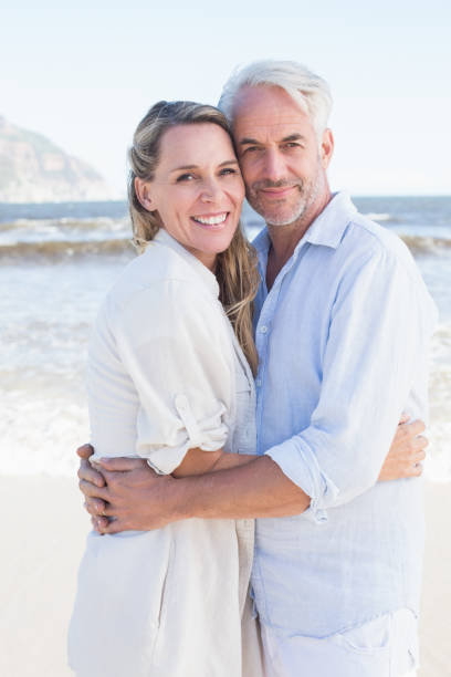 istock Happy couple hugging on the beach looking at camera 692200422