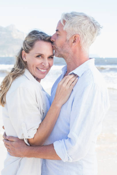 istock Man kissing his smiling partner on the forehead at the beach 692200854