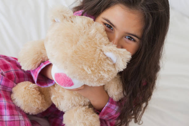 istock Smiling girl with stuffed toy sitting on bed 692200874