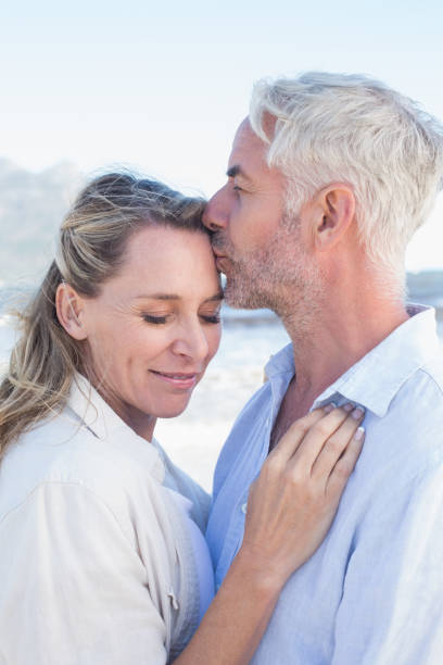 istock Man kissing his smiling partner on the forehead at the beach 692200904