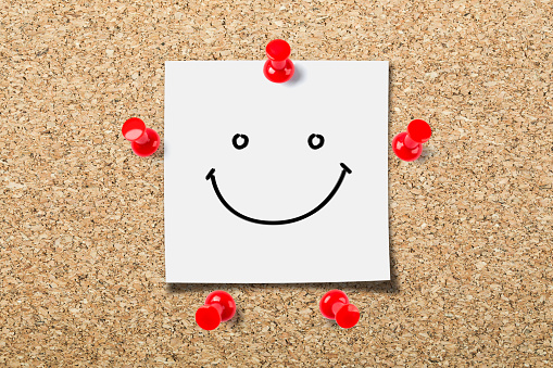 Cork board with a smile face sticky notes.