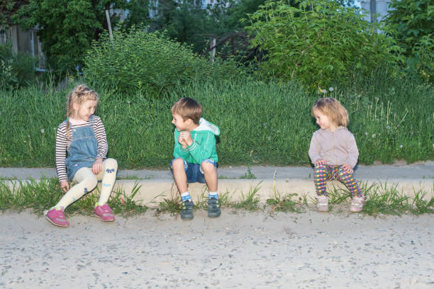 Cute little girl is looking at her older brother while holding wireless headphones.